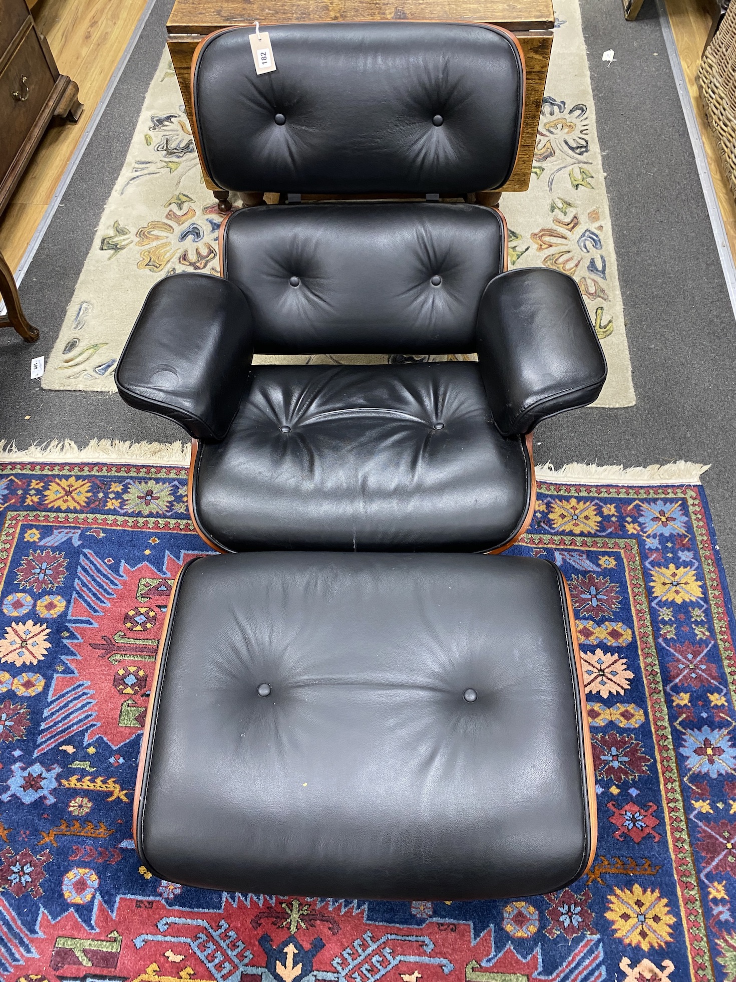 An Eames style recliner armchair and footstool